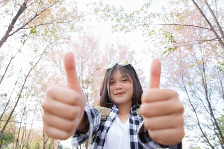 Happy woman traveler relax feel free with cherry blossoms tree on vacation, tourism and holiday conceptの写真素材