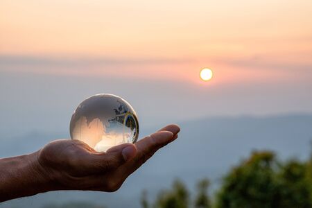 Crystal ball photography - sunset mountain, hand holding the ballの写真素材