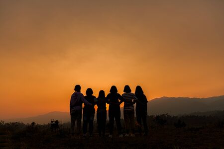 Group of happy people playing at summer sunset in nature