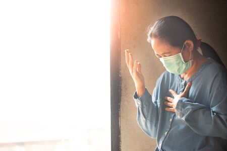 Asian woman wearing medical mask and praying for whole people in the world which got infected by novel Coronavirus, Covid-19 to get recovered soon.の写真素材