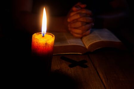 Praying woman hands on old holy bible sacred book in a dark church during a prayer worship service...