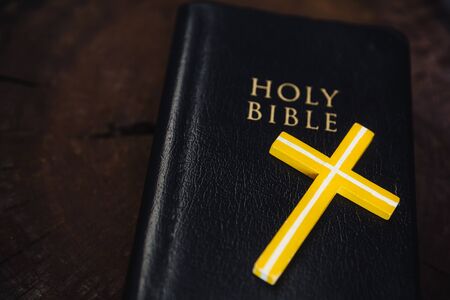 Crucifix and Holy Bible on wooden table. Black holy bible with crucifix. Concept of religious events or exorcismの写真素材