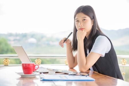 Beautiful young woman working on laptop computer while sitting at the roof deck, drinking coffee