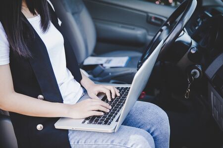 Beautiful businesswoman using laptop while sitting in car.の写真素材