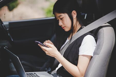 Beautiful business woman is using a smart phone and while sitting on back seat in the carの写真素材