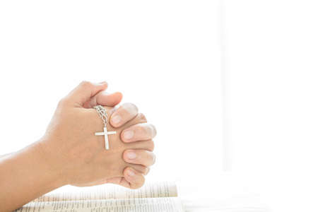 Close up woman hands with cross in his hands praying a God. Prayer time on sunday.
