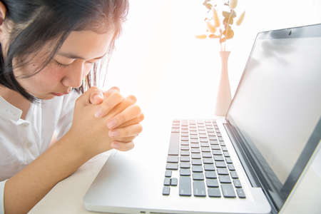 Asian girl praying with computer laptop, Church services new normal concept, Home church during...