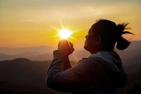 Silhouette woman on sunset background. Woman raising his hands in worship. Christian Religion...