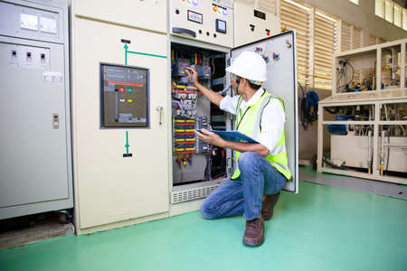 Maintenance engineers inspect relay protection system. Bay control unit. Medium voltage switchgear