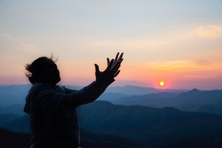 Silhouette woman on sunset background. Woman raising his hands in worship. Christian Religion...