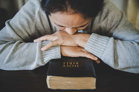 Hands folded in prayer on a Holy Bible in church concept for faith, spirituality and religion, woman praying on holy bible in the morning. woman hand with Bible praying.の写真素材