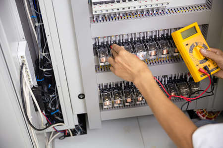 Electrician engineer work tester measuring voltage and current of power electric line in electical...