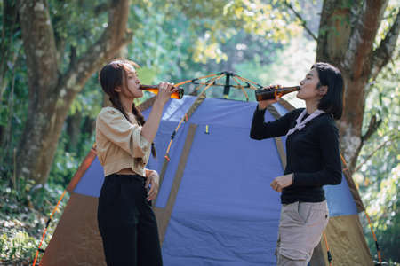 two bestie having fun together Relax in hiking camp and drinking beer Cheers bottles And Enjoying....