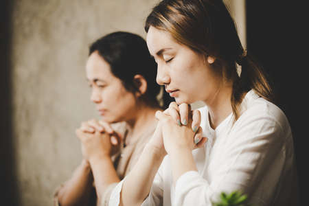 Two women praying worship believe. soft focus, praying and praise together at home. devotional or prayer meeting concept.の写真素材