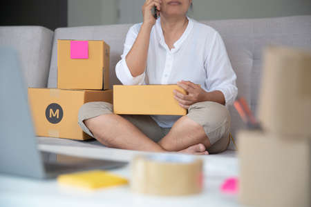 Woman owner business woman work at home or office with smartphone, laptop for online shopping writing the order.の写真素材