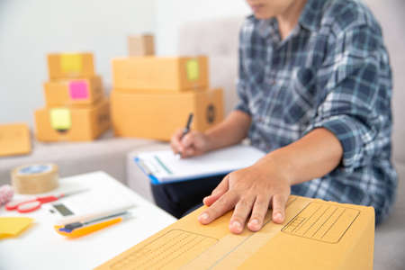 Asian female entrepreneur SME owner checks online orders to take customer orders and pack products into boxes. Online Business Ideas and Freelanceの写真素材