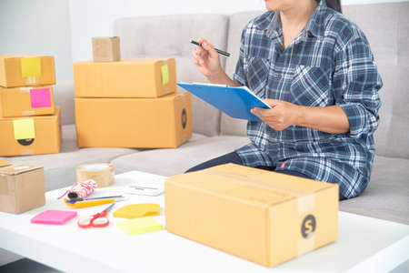 Asian female entrepreneur SME owner checks online orders to take customer orders and pack products into boxes. Online Business Ideas and Freelanceの写真素材