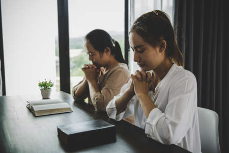 Two women praying worship believe. soft focus, praying and praise together at home. devotional or prayer meeting concept.の写真素材