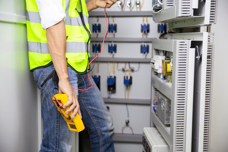 Electrician engineer work tester measuring voltage and current of power electric line in electical cabinet control.の写真素材