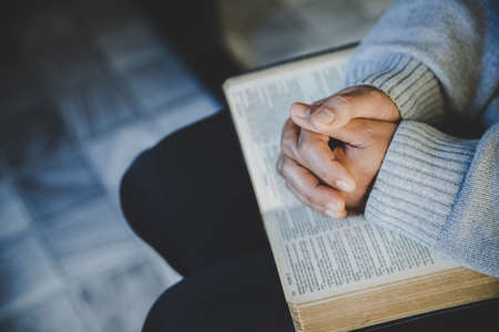 Hands folded in prayer on a Holy Bible in church concept for faith, spirituality and religion, woman praying on holy bible in the morning. woman hand with Bible praying.の写真素材