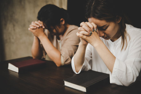 Two women praying worship believe. soft focus, praying and praise together at home. devotional or prayer meeting concept.の写真素材