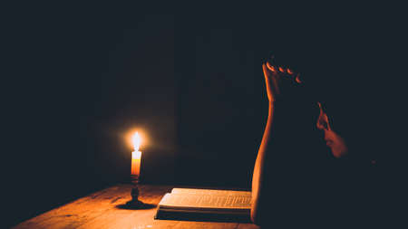 Woman praying in the light candles selective focus. Beautiful gold background. Religion concept.