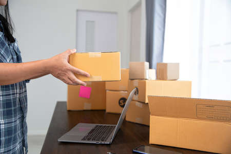 Closeup view of female online store small business owner seller entrepreneur packing package post...