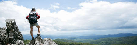 Young person hiking female standing on top rock, Backpack woman looking at beautiful mountain in...