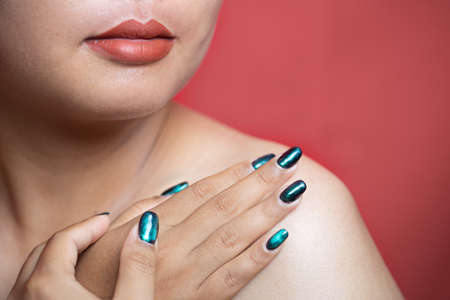 Beauty model girl with green manicure nails. Woman Fashion makeup and care for hands cosmetics. Health care. Beauty spa salon. Clean smooth skin, Nude lips. hand near the faceの写真素材