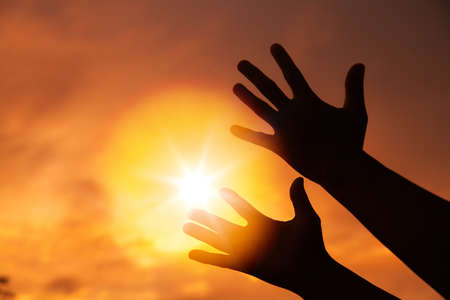 Person human hands open palm up worship or pray for god. background is sunrise. Concept for...