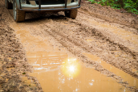 Wheel truck closeup in countryside landscape with muddy road. Extreme adventure driving 4x4 vehicles for transport or travel or off-road races in outdoor nature. 4wd tire automobile on dirt mountain.の写真素材