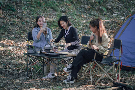three bestie go camping in the forest and take a photos while cookingの写真素材