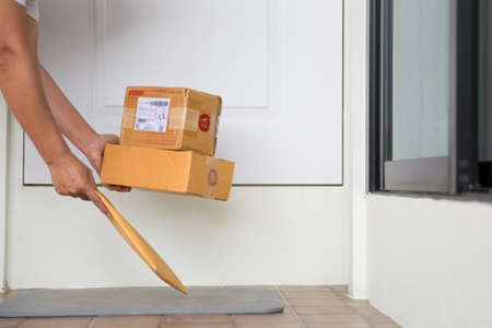 Woman collects parcel at door. box near door on floor. Online shopping, boxes delivered to your front door. Easy to steal when nobody is home. Parcel in cardboard box on doorstep. Delivery serviceの写真素材