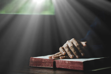 Hand folded in prayer to god on Holy Bible book in church concept for faith, spirituality and religion, woman person praying on holy bible in morning. christian catholic woman hand with Bible worship.の写真素材