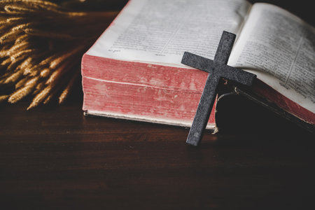Holy bible book with cross or crucifix on old black wooden background. Christian catholic with protestant pray and study in church. Concept of cognition about faith god and religion, jesus spiritual.の写真素材