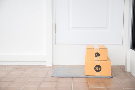 Cardboard parcel box near door on floor. Online shopping, boxes delivered to your front door. Easy to steal when nobody is home. Parcel in cardboard box on doorstep. Delivery serviceの写真素材