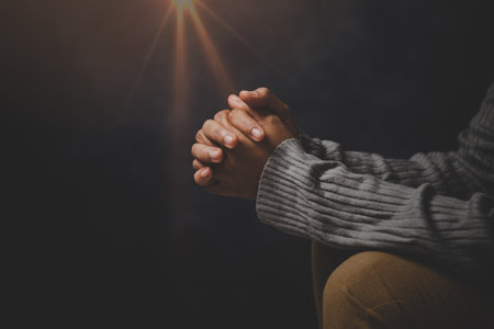 Christ religion and christianity worship or pray concept. Christian catholic woman are praying to god in dark at church. Prayer person hand in black background. Girl believe and faith in jesus christ.の写真素材