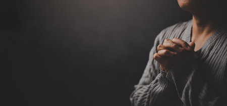 Christ religion and christianity worship or pray concept. Christian catholic woman are praying to god in dark at church. Prayer person hand in black background. Girl believe and faith in jesus christ.の写真素材
