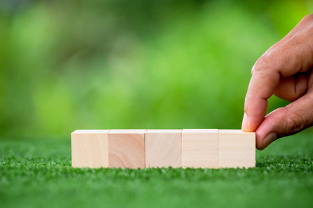Stacking blank wooden cubes on green background with copy space for input wording and infographic icon. Empty brown wooden object block for symbol icon put technology, zero gravity, business concept.の写真素材