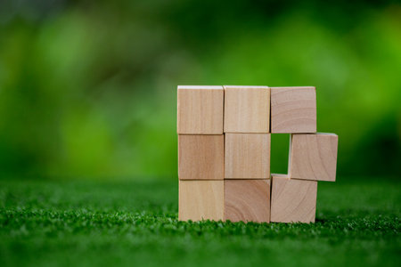 Stacking blank wooden cubes on green background with copy space for input wording and infographic icon. Empty brown wooden object block for symbol icon put technology, zero gravity, business concept.の写真素材