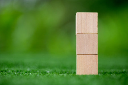 Stacking blank wooden cubes on green background with copy space for input wording and infographic icon. Empty brown wooden object block for symbol icon put technology, zero gravity, business concept.の写真素材
