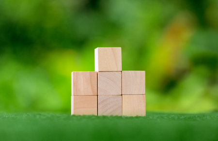 Stacking blank wooden cubes on green background with copy space for input wording and infographic icon. Empty brown wooden object block for symbol icon put technology, zero gravity, business concept.の写真素材