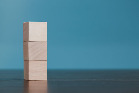Stacking blank wooden cubes on blue background with copy space for input wording and infographic icon. Empty brown wooden object block for symbol icon put technology, zero gravity, business concept.の写真素材