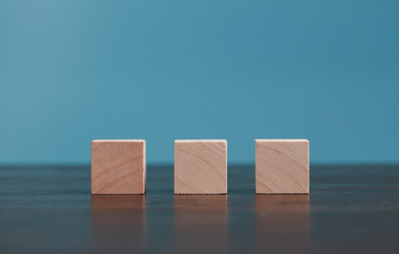 Stacking blank wooden cubes on blue background with copy space for input wording and infographic icon. Empty brown wooden object block for symbol icon put technology, zero gravity, business concept.の写真素材