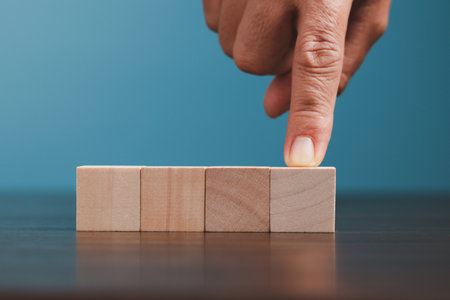Stacking blank wooden cubes on blue background with copy space for input wording and infographic icon. Empty brown wooden object block for symbol icon put technology, zero gravity, business concept.の写真素材