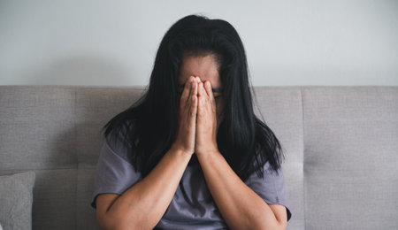 Schizophrenia with lonely and sad in mental health depression concept. Depressed woman sitting against on the sofa at home with dark room feeling miserable. Women are depressed, fearful and unhappy.の写真素材