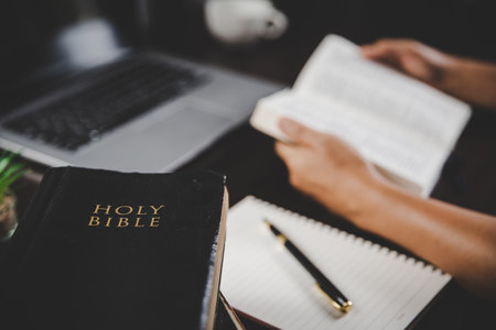 Young woman person hand holding holy bible with study at home. Adult female christian reading book...