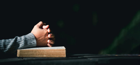 Prayer person hand in black background. Christian catholic woman are praying to god in dark at church. Girl believe and faith in jesus christ. Christ religion and christianity worship or pray concept.の写真素材