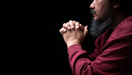 Hands folded in prayer on in church concept for faith, spirituality and religion, man praying in the morning. man hand with praying god. Person Christian men who have faith in Jesus worship in dark.の写真素材