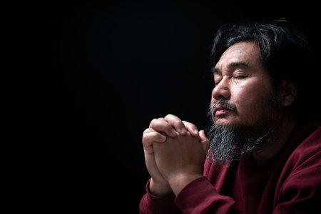Hands folded in prayer on in church concept for faith, spirituality and religion, man praying in the morning. man hand with praying god. Person Christian men who have faith in Jesus worship in dark.の写真素材